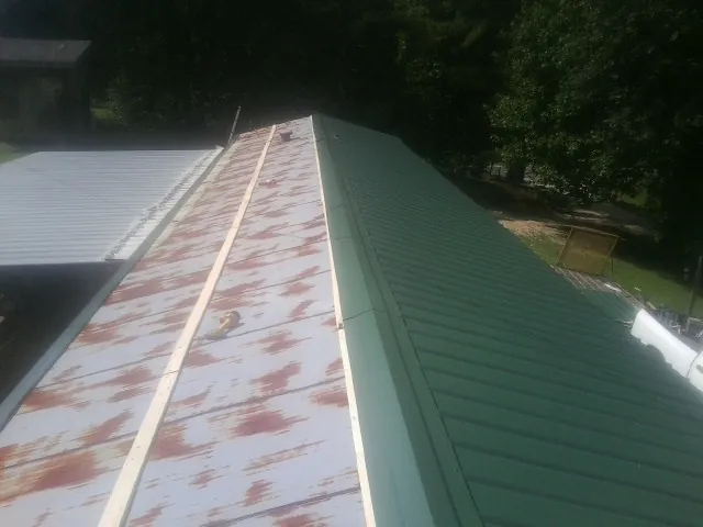 Old rusted panels beside newly installed green metal roofing — Wind Damage Roof Repair by Roofing Brothers in Poynette