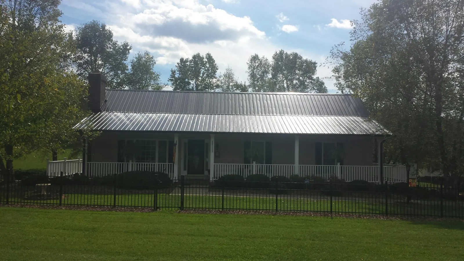 Gray metal roof on a brick ranch with a full width front porch — Gutter Guard Installation work by our crew in Poynette