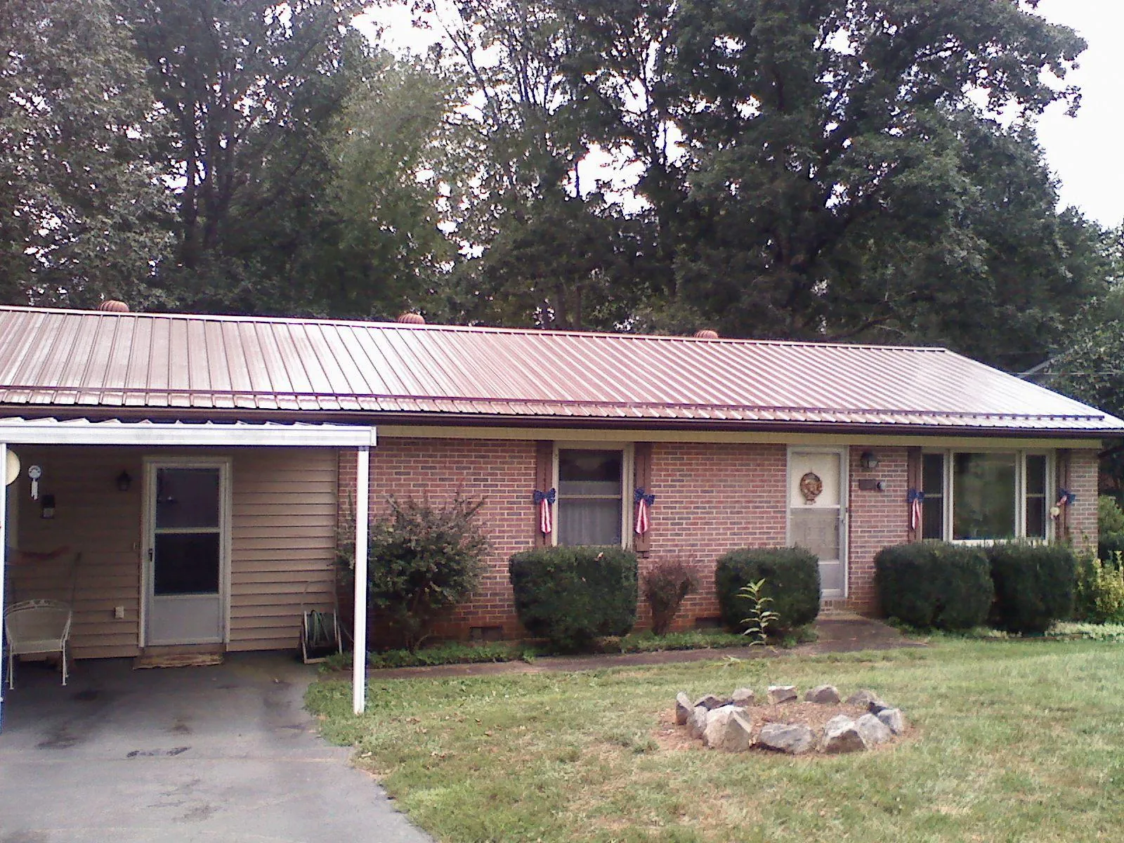 Bronze metal roof and carport on a brick ranch home — Roof Repair work by our crew in Poynette