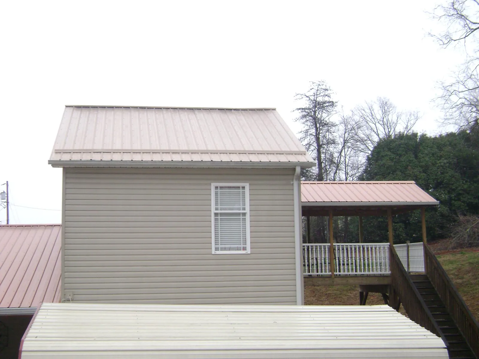 Tan metal roofs on a two story addition and attached porch, from a Roof Replacement job in Poynette