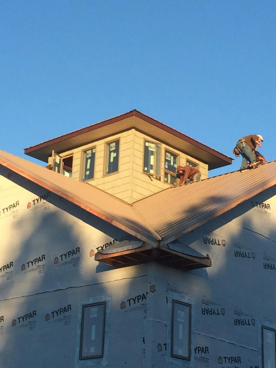 Roofers working around a rooftop cupola on a new metal roof at sunset — Roof Waterproofing in Poynette by Roofing Brothers